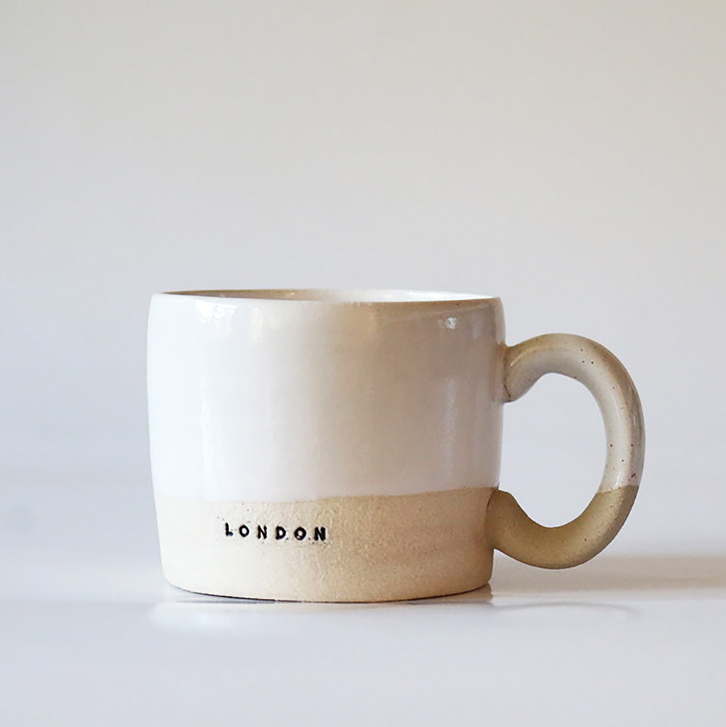 Handcrafted ceramic mugs in various colors, with 'LONDON' and a postcode stamped on them.