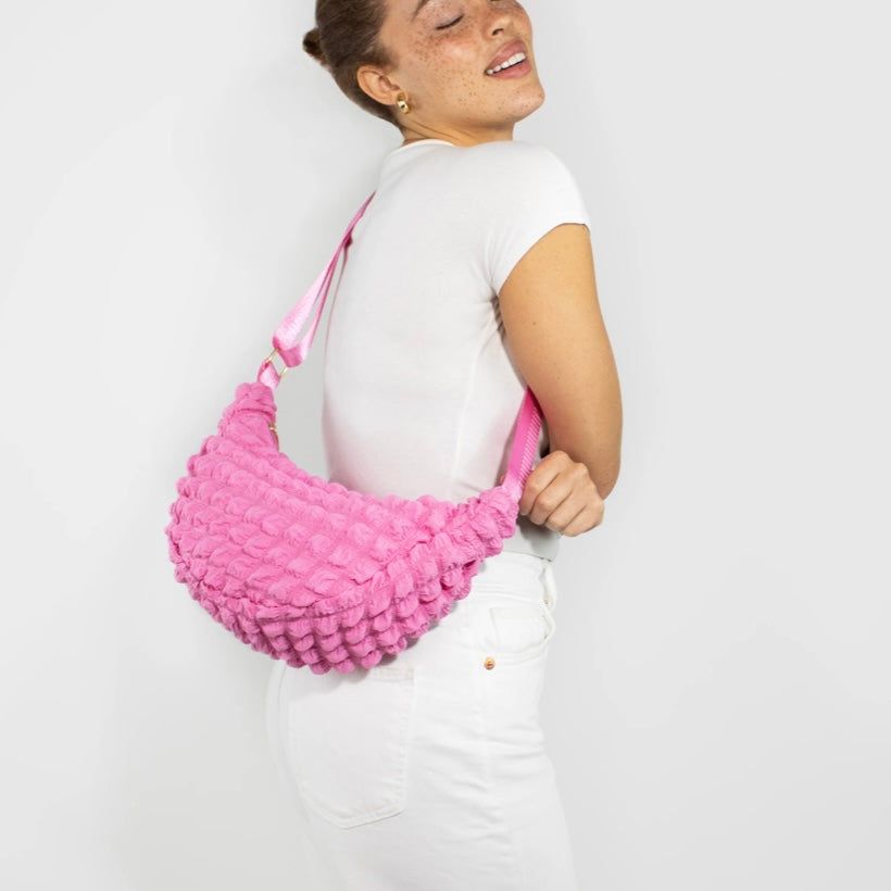 Kind Bag crossbody bag in bold pink waffle texture – playful and vibrant design made from recycled materials