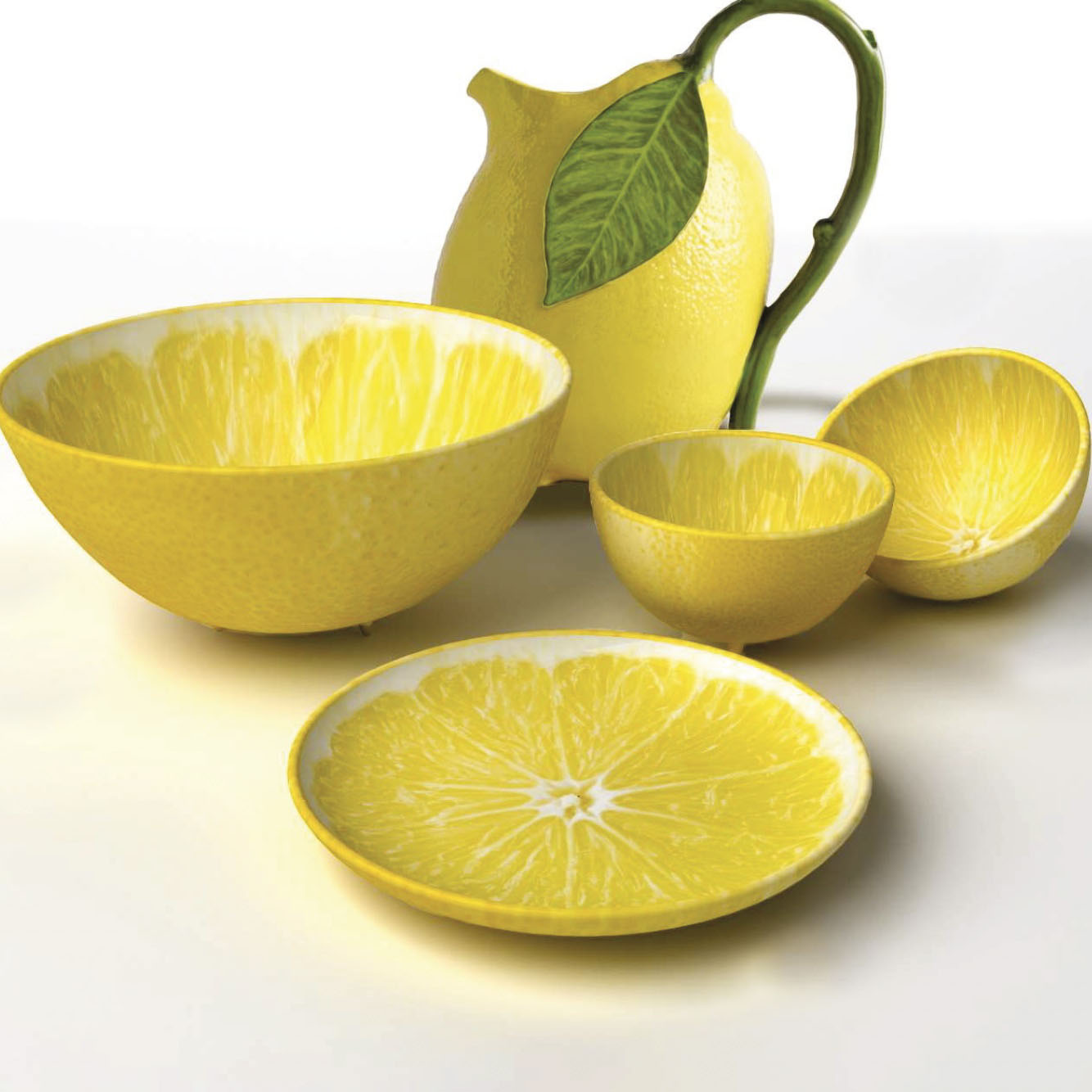 Three yellow ceramic bowls shaped like half lemons by Bordallo Pinheiro with a textured exterior, and a lemon-inspired plate and pitcher against a white background.